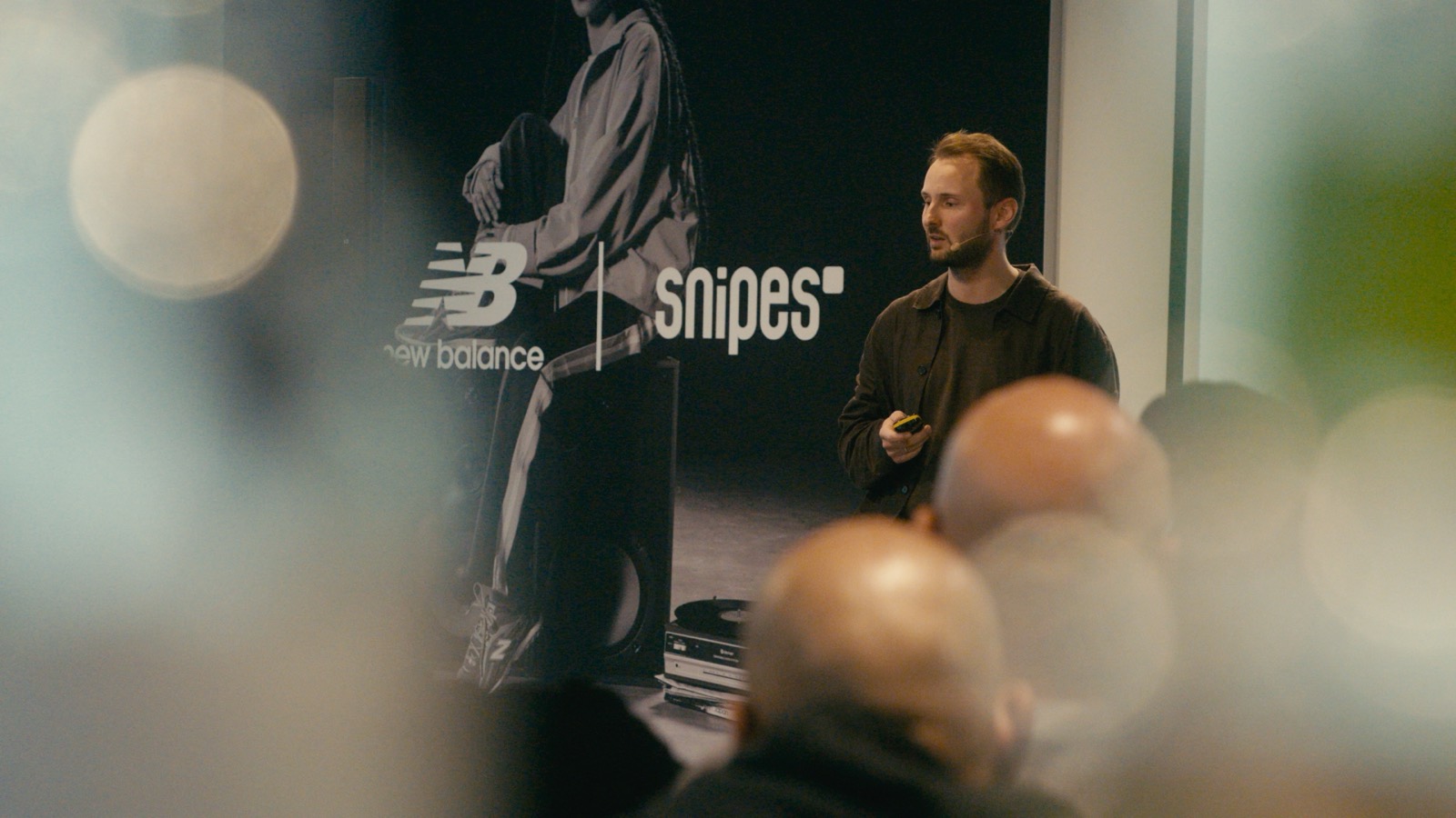 A speaker presenting in front of the New Balance x Snipes backdrop